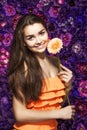 Brunette woman with a gentle make-up that looks at the camera while holding flower near the face on a floral background. Royalty Free Stock Photo