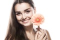 Brunette woman with a gentle make-up that looks at the camera while holding flower near the face on a isolated Royalty Free Stock Photo