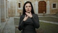 Brunette woman gesturing expressively on university campus with historic architecture in background Royalty Free Stock Photo