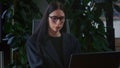 Brunette woman in glasses works diligently on contemporary laptop in office