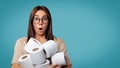 Brunette woman in glasses holds a lots of toilet paper, she opened her mouth in a surprise, copy space, isolated over Royalty Free Stock Photo