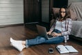 Brunette woman in glasses sitting  on the floor and working with laptop at home. Royalty Free Stock Photo