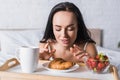 Brunette woman having croissant, strawberry and