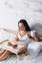 Brunette woman having croissant, strawberry and