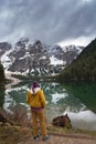 A brunette woman hiker, wearing outdoor gear is standing looking out at the view on Lake Braies