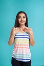 Brunette woman with long hair, dressed in striped shirt and black leggings, posing against blue studio background Royalty Free Stock Photo