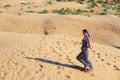 brunette woman in a long leopard dress walk with her back in the desert at sunset. go everywhere. Royalty Free Stock Photo