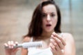 Brunette woman looking frightened when sees a lot of fallen hair on the brush hair loss problem