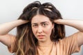 The brunette woman nervously scratches her head suffering from itching. White background. The concept of dandruff and pediculosis