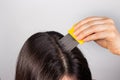 A brunette woman with pediculosis cleans her hair from lice and nits with a comb with small prongs. A lice comb