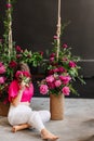 a brunette woman in a pink blouse with peonies and a swing.