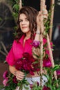 a brunette woman in a pink blouse with peonies on the swing.