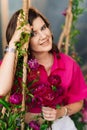 a brunette woman in a pink blouse with peonies on the swing.