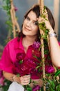 a brunette woman in a pink blouse with peonies on the swing.