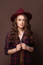 Brunette woman in plaid shirt and fedora hat on brown background Royalty Free Stock Photo