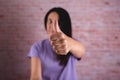 Brunette woman raising a thumb on a brick wall background Royalty Free Stock Photo