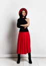 Brunette woman in red and black clothes and hat stands with arms crossed. In maxi skirt, jackboots and wide-brimmed hat Royalty Free Stock Photo