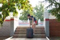 A brunette woman in red shorts hardly lifts a large heavy suitcase up the steps at the train