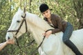 Brunette woman riding dark horse at summer green forest. Royalty Free Stock Photo