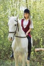 Brunette woman riding dark horse at summer green forest. Royalty Free Stock Photo