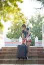 A brunette woman shorts hardly lifts a large heavy suitcase up the steps at the train