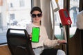 brunette woman showing smartphone with vertical green screen in tram