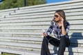 Brunette woman sitting on stairs while listning music and using Royalty Free Stock Photo