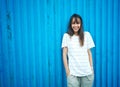 Brunette woman smiling to camera and looking happy, standing by bright blue wall on background