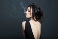 Brunette woman Smoking on dark background in black dress. Erotic girl Royalty Free Stock Photo