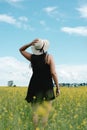 Brunette woman standing field of yellow wild flowers on a summer day Royalty Free Stock Photo