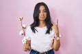 Brunette woman standing over pink background pointing up looking sad and upset, indicating direction with fingers, unhappy and Royalty Free Stock Photo