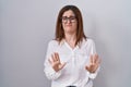 Brunette woman standing over white isolated background moving away hands palms showing refusal and denial with afraid and