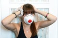 Young woman wearing N95 respirator. Stressed out due to self isolation in times of Coronavirus