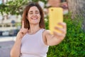 Brunette woman taking a selfie photo with smartphone smiling with an idea or question pointing finger with happy face, number one