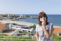 Brunette woman throwing a kiss in front of a seabed, beach in Ca