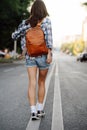 Brunette woman walking on the road, wearing brown leather backpack
