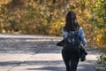 Brunette woman walks along the alley of an autumn park. Lonely girl in the sunny forest. Back view