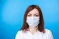 Brunette woman wearing aseptic mask. light blue background