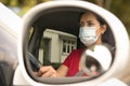 Brunette woman wearing face mask driving her car through the side mirror car. Covid-19 Corona virus Royalty Free Stock Photo