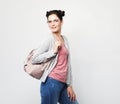 Young brunette woman wearing a pink t-shirt and jeans is holding a backpack and smiling