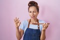 Brunette woman wearing professional cook apron holding wooden spoon winking looking at the camera with sexy expression, cheerful Royalty Free Stock Photo