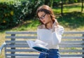 Brunette woman wearing white clothes, reading book, sitting at summer green park Royalty Free Stock Photo