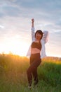 brunette woman in white blouse with baldric on summer field on sunset. peaceful time. millennial generation. calm female