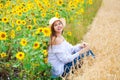 Brunette woman in white blouse sitting on a background of golden wheat and sunflowers fields Royalty Free Stock Photo