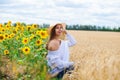 Brunette woman in white blouse sitting on a background of golden wheat and sunflowers fields Royalty Free Stock Photo