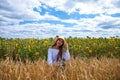 Brunette woman in white blouse sitting on a background of golden wheat and sunflowers fields Royalty Free Stock Photo