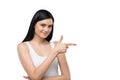 Brunette woman is in a white tank top and blue denims. She points out the copy space. Royalty Free Stock Photo