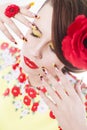 Brunette woman in yellow and red dress with poppy flower in her hair, poppy ring and creative nails, closed eyes Royalty Free Stock Photo