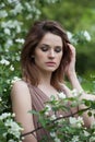 Brunette young adult woman female model with clean fresh skin, make-up and brown hair in blossom garden on green leaves background Royalty Free Stock Photo