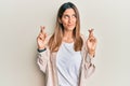 Brunette young woman doing fingers crossed gesture smiling looking to the side and staring away thinking Royalty Free Stock Photo